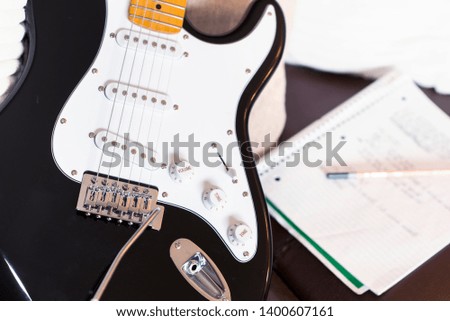 Guitar songwriting at home. Notepad and pencil with electric guitar close up