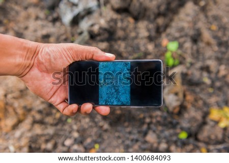 farmer using mobile take a photo to earth  agriculture in farm .agriculturist with smarthphone in hand - Image