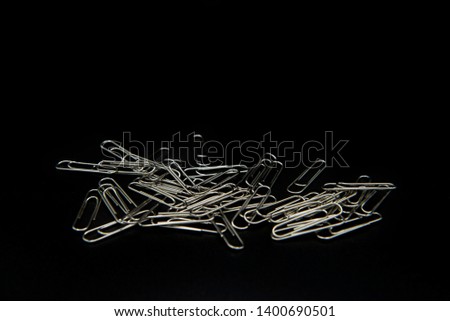 Many paper clips are placed on a black background.