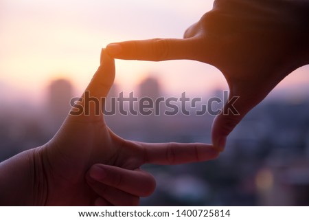 Photo sign made by human hands on blurred sunset sky as background 