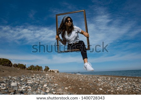 Young girl is holding empty frame and going through it. Double exposure