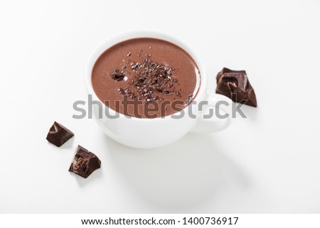 Hot chocolate drinks and chocolate pieces in white cup.