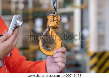 Engineers are inspecting hooks for lifting safety crane steel In the factory auto parts license Crane Operation chain equipment Orange photograph Royalty-Free Stock Photo #1400741423