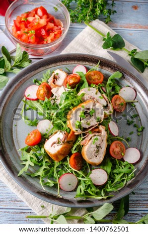 Delicious chicken roulade filled with herbs and ham, fresh salad with radishes