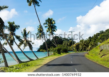 Tropical scenery view on beach in Polynesia with coconut palm trees, perfect white sand, in foreground, ocean with turquoise water and deep blue sky with clouds. Royalty-Free Stock Photo #1400769932