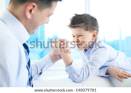 Photo of little boy and his dad armwrestling