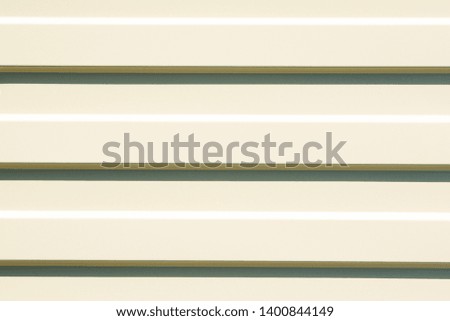 Light yellow profiled sheet metal on a Sunny day with parallel horizontal shadows