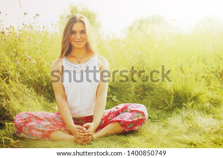 Young plump woman doing yoga in grass.