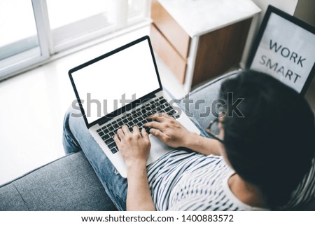 mockup image computer screen with blank space for text,sitting on sofa typing using laptop contact business searching information in workplace.design creative work space on wooden desktop