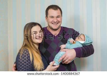 Woman and man holding a newborn. Mom, dad and baby. Portrait of young smiling family with newborn on the hands