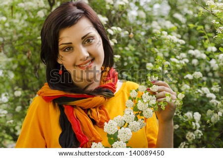 Portrait of smiling beautiful girl in flowers with picture on face