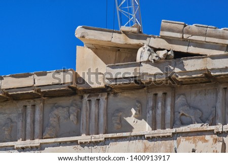 Sculpture of Selene's horse head on the parthenon's frieze of Athens Acropolis with white building crane in the background.