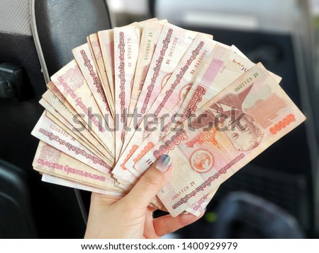 Focus on the left hand of Asian women holding money of laos with blur background.