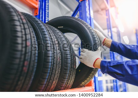	
Asian male tire changer In the process of checking the condition of new tires in stock so that they can be replaced at a service center or auto repair shop. Tire warehouse for the car industry	
