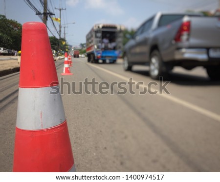 Traffic cones are on the road with cars. 