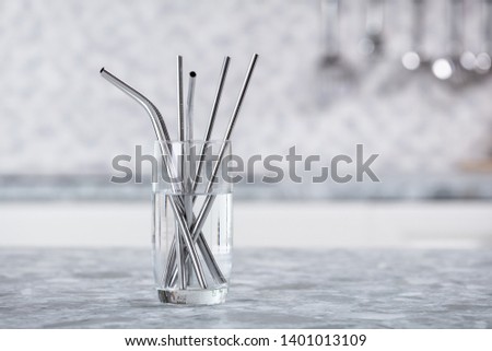 Metal Straws In Transparent Glass Of Water On Kitchen Worktop Royalty-Free Stock Photo #1401013109