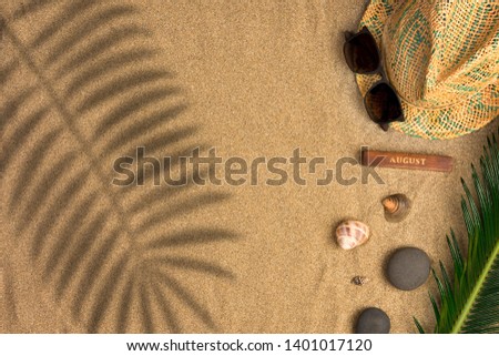 Stylish summer composition with green leaves, hat and sunglasses on a sand background with shadows. Artwork mockup with copy space