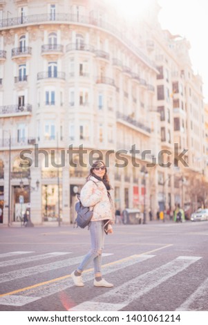 Young smiling woman crossing the road - girl walking down the street in a big city