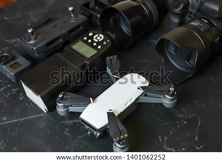 Set of videographer on a black background. Digital camera, memory card, action camera, drone, remote control and camera. Top view on black background table.