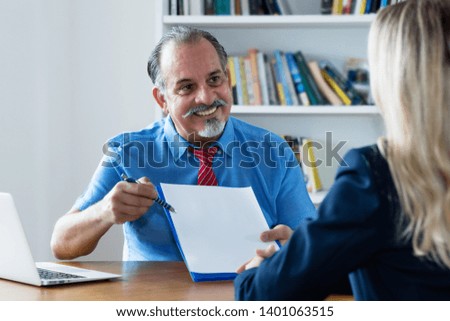 Senior businessman presenting contract to new employee at office of company