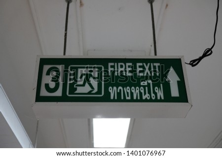 Fire exit sign with English and Thai languages  on the ceiling office/ building/ emergency