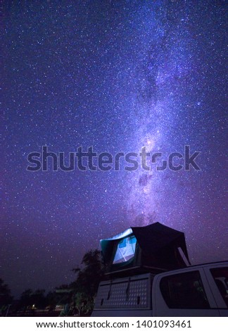 Milky way over a tent located on the roof of a pickup car in the Namib desert of Namibia. Night photo with many stars.