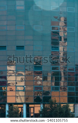 high-rise buildings of the big city are reflected in the glass facade.