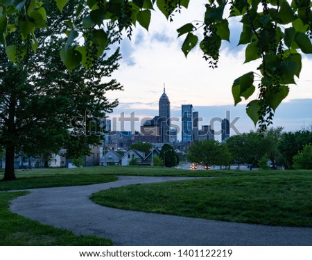 Walking path and the Indianapolis skyline framed by trees in late evening