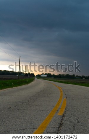 Open country road with storm clouds approaching in rural Illinois.
