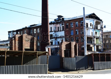 A photo of a background with a construction site enclosed by a triad metal fence. Old dilapidated building.
Factory brick pipe