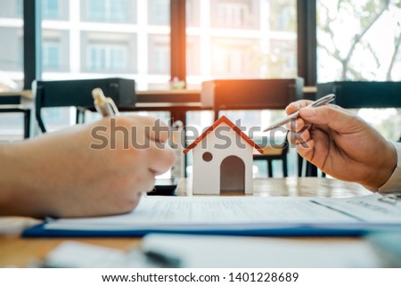 house model on back of real estate agents submit documents for customers to sign for a sale contract,real estate concept.