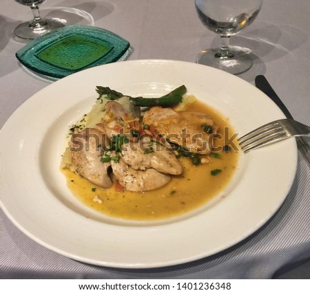 Chicken with asparagus served over mashed potatoes with rosemary sauce and topped with pine nuts, capers and parsley
