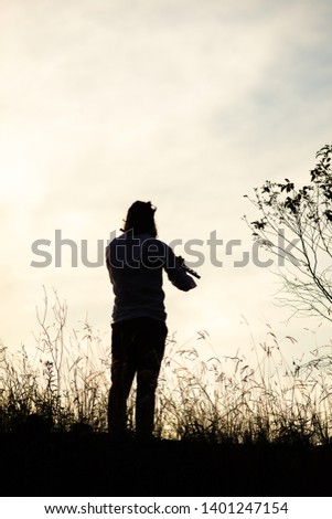 a piper playing a c flute against a hard sun in the background amidst a country setting