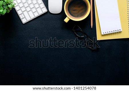 Dark leather office desk with cup of coffee, white keyboard, mouse, pencil, glasses and yellow notebook. Top view. Tabletop. Copy space.