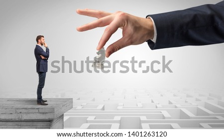 Little businessman from the top of the labyrinth fixing long term plan with big hand and chessman concept