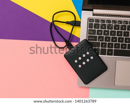 External hard drive labeled database connected to laptop on colorful background. The view from the top. The concept of backup storage. Flat lay.