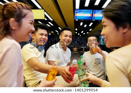 Happy young Asian people enjoying soft drinking after playing bowling