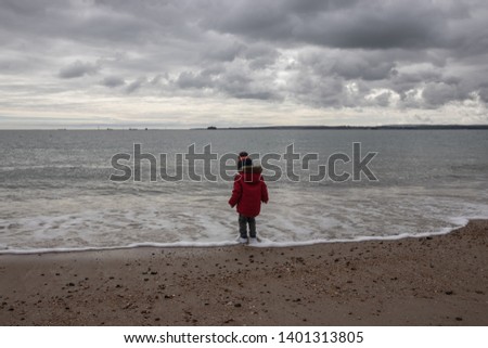 a young boy in winter clothing playing on a sandy beach in winter 