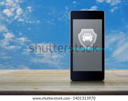 Car with shield flat icon on modern smart mobile phone screen on wooden table over blue sky with white clouds, Business automobile insurance online concept