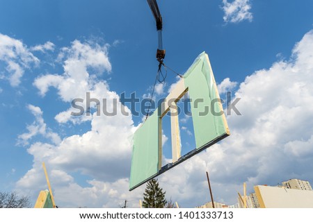 Process of construction new and modern modular house from composite sip panels. Low view angle photo of crane with sip panel against sky and blue background