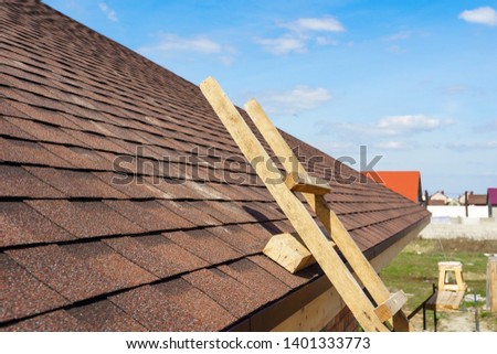 Photo of asphalt tile roof with wooden and safety ladder on new home under construction