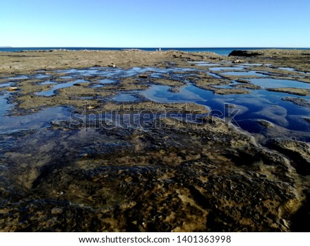 picture of argentinian cliffs looking at the ocean with water pounds mirroring the sky. Picture taken in puerto piramides