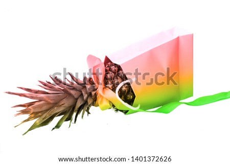 Pineapple with ribbon in  paper bag on white isolated background. Festive decor. Closeup, copy space.