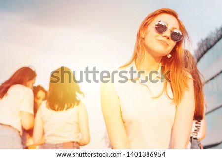 Positive beautiful happy red haired girl in the mirror sunglasses with friends on blue sky background, the summer sunset time