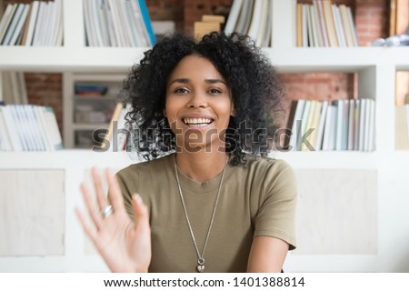 Happy african American millennial woman wave talk on webcam or having conversation, smiling positive black female blogger shoot record new blog or vlog, greeting say hello to followers audience Royalty-Free Stock Photo #1401388814