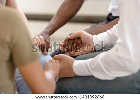 Close up of diverse religious people sit in circle hold hands pray together hope for help, multiracial men and women group gathering express support and understanding at psychological therapy session Royalty-Free Stock Photo #1401392666