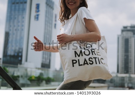 Urban lifestyle and safe environment concept. Cropped head side on portrait of young hipster lady walking around town with eco bag putting thumb up Royalty-Free Stock Photo #1401393026