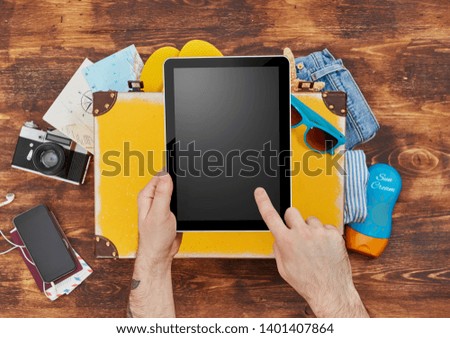 Man holding a digital tablet and packing for vacation