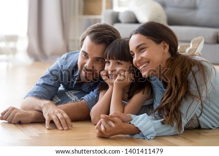 Happy young family with cute preschooler daughter lying on floor at home pose for picture, loving smiling parents make photo together with small girl child, little kid photograph with mom and dad