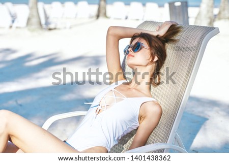 pretty woman in a white swimsuit is relaxing in a sunbed sunbath nature